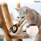 A white cat inspecting a brown and white plush Petifo moving bird toy resting on a scratching post platform.