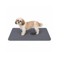 Shih Tzu puppy using a waterproof and absorbent grey pet training mat indoors.