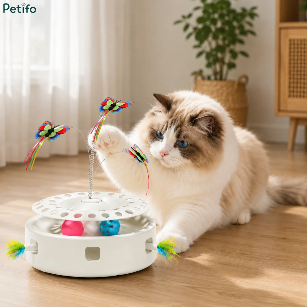 A fluffy ragdoll cat reaching out to swat at the fluttering butterfly attachment on an automatic electronic cat toy.