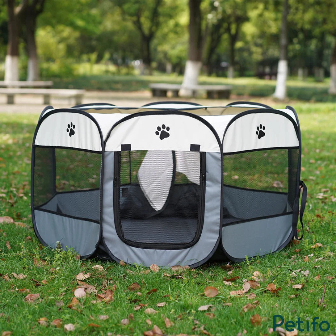 Beige and gray Petifo portable pet playpen set up outdoors on a green grass lawn with trees in the background.