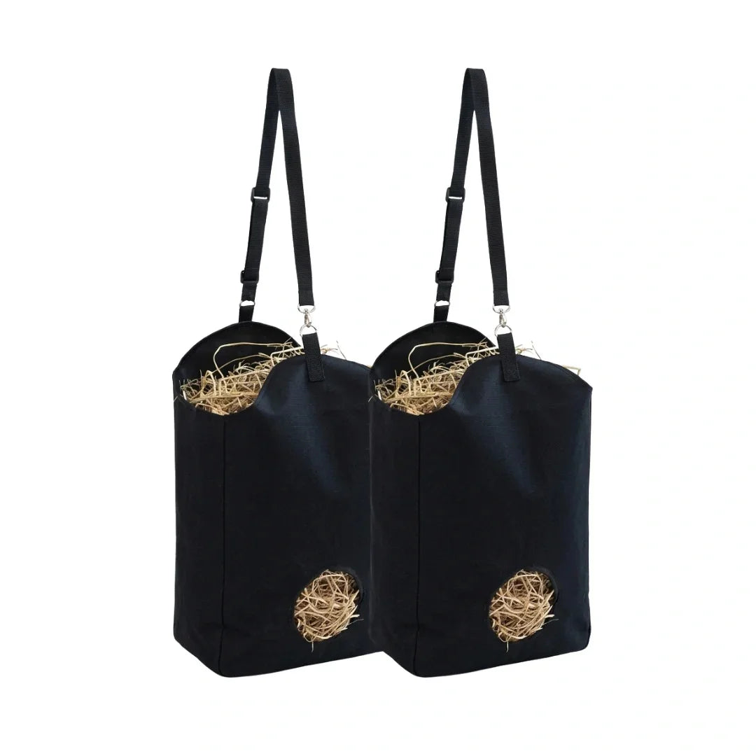 Two black hanging hay feeder bags filled with dry straw on a white background.