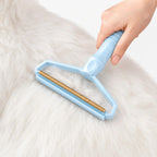 Blue pet hair remover tool gliding smoothly across a thick white coat of pet hair.