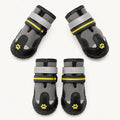 Complete set of four grey and black dog shoes featuring adjustable straps and yellow paw print embroidery on a white background.