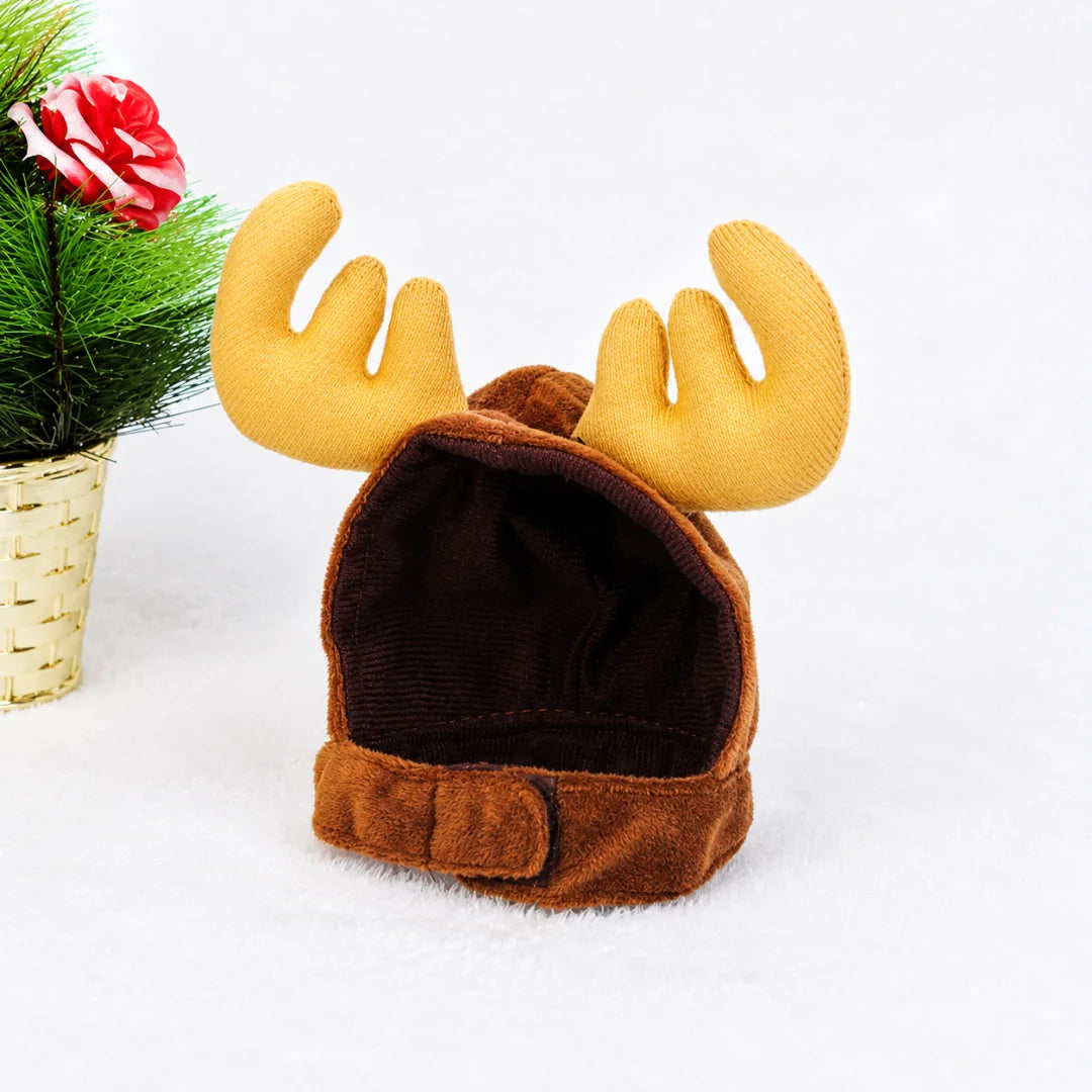 Brown plush pet hat with soft yellow reindeer antlers and a small decorative plant beside it.
