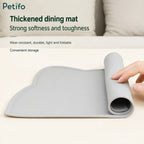 A hand rolling up the flexible gray silicone pet dining mat to showcase its soft, durable, and fold-friendly storage design.