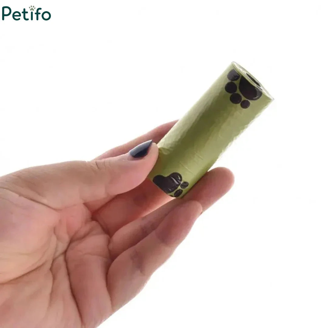 Close-up of a single roll of green paw-print dog poop bags held in a hand.