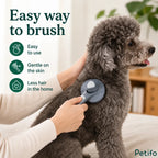 Person gently brushing a fluffy grey poodle with the Petifo self-cleaning pet brush to reduce loose hair in the home.