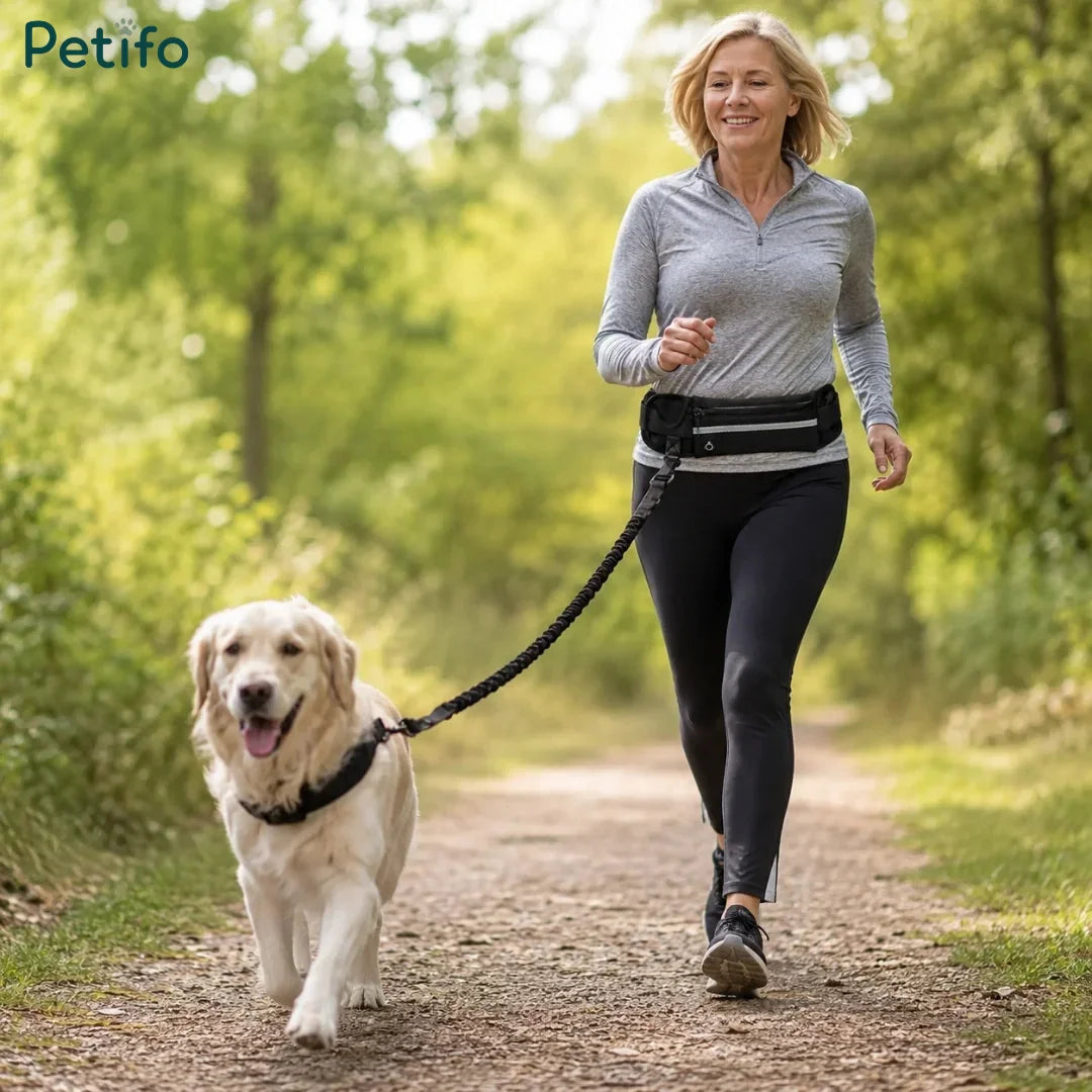 Woman jogging along a park path while walking her golden retriever using a hands-free waist leash.