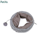 Collapsed and folded grey plush cat tunnel with a hanging toy ball for easy storage.