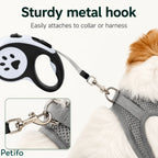 A close-up view of a sturdy metal hook securely attaching a retractable leash to a dog's mesh harness.
