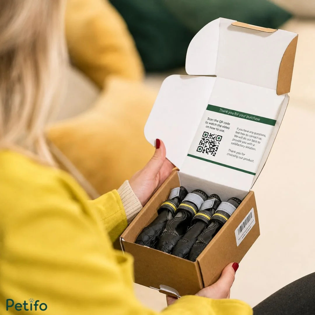 Person in a yellow sweater opening a packaged box containing new dog boots with an instructional QR code printed on the inside lid.
