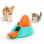 Petifo teal and orange interactive treat launcher toy isolated on a white background, accompanied by a Corgi dog on the left and a playful gray kitten on the right.