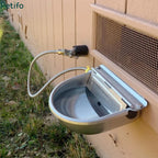 Fully installed automatic stainless steel livestock water bowl connected to an outdoor water supply line against a wall.