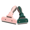 Pink and green pet deshedding brushes displayed side by side on a clean white surface.