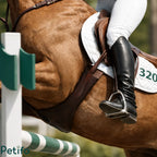 Action shot of a rider wearing tall black boots using the stirrup while jumping over an obstacle.
