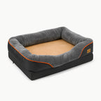 A sleek, rectangular orthopedic dog bed in charcoal grey with an orange accent trim and a plush, tan-colored sleeping surface