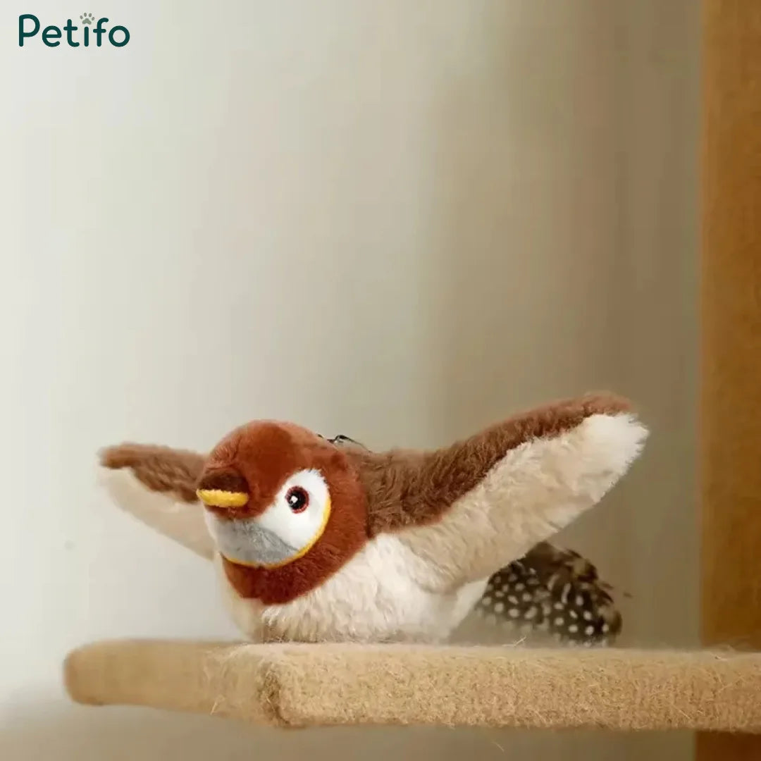 Studio product shot of the plush Petifo interactive bird toy with outstretched wings and a feathery tail, resting on a scratching post surface.