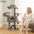 Three happy cats relaxing on different levels of a sturdy, plush grey cat tree in a cozy living room setting.