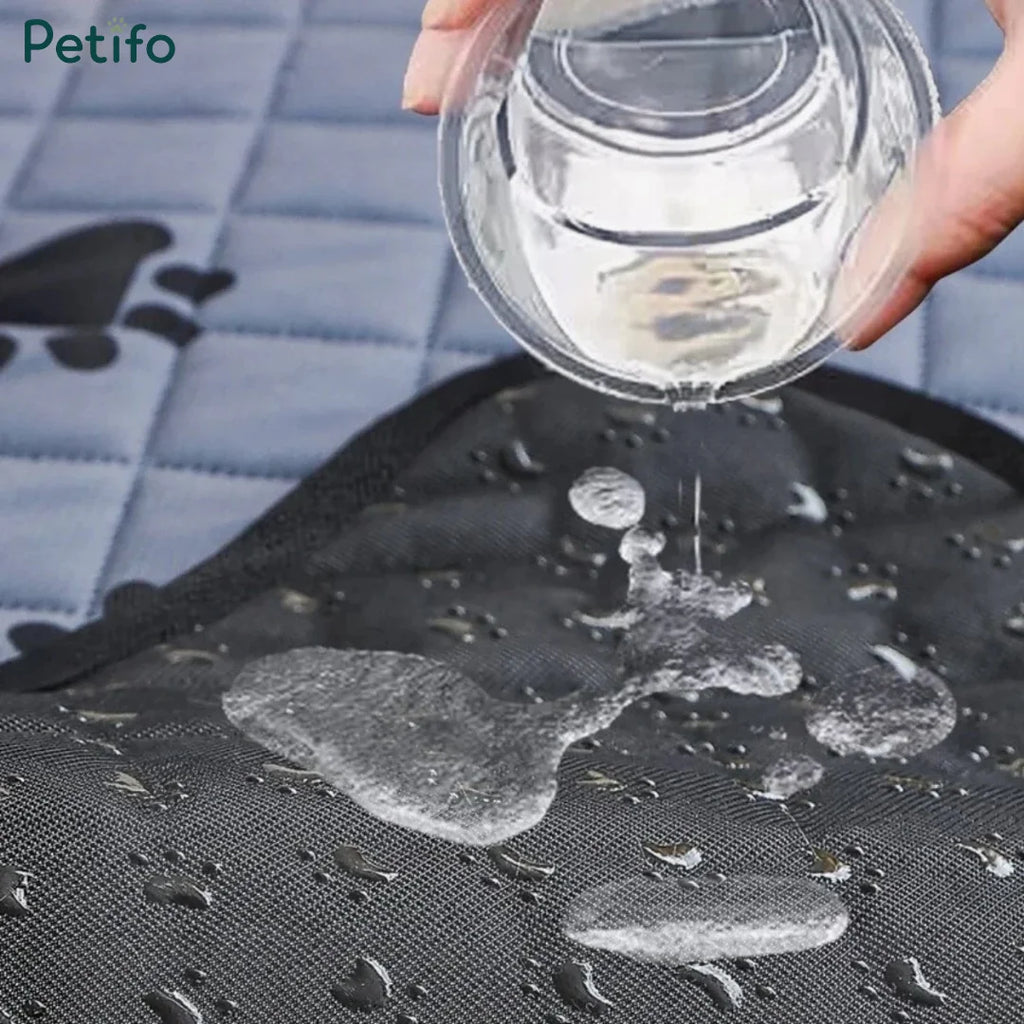 Water being poured onto a black waterproof pet training mat to demonstrate liquid resistance and absorption.