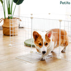 Corgi dog stepping out of a Petifo white wire playpen with an open door panel indoors.